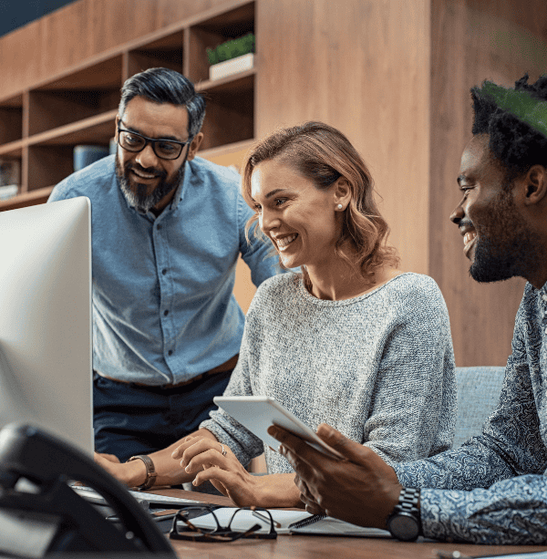 A group of employees work together on a computer.