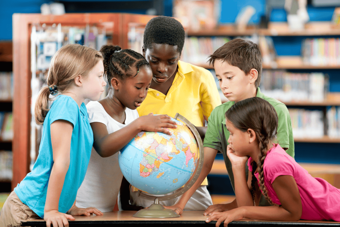A group of five students are gathered around a globe and are looking at the various countries.